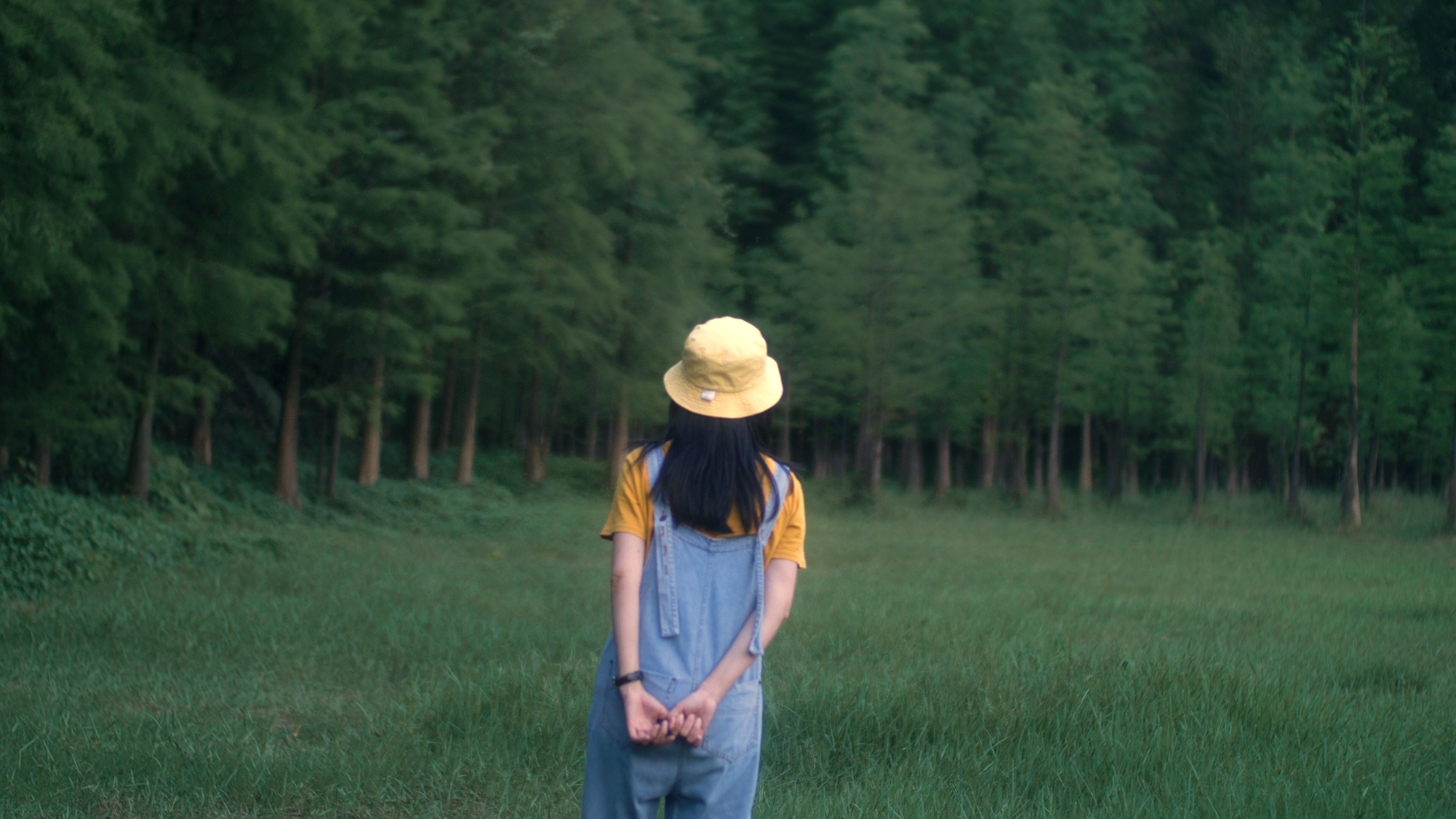 牛仔背带裤女孩在树林行走4k视频素材