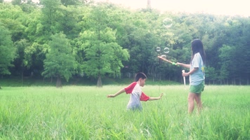 孩子在草地玩耍吹泡泡奔跑4k视频素材