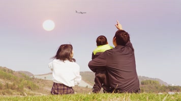 一家三口仰望天空手指飞机眺望远方温馨家庭