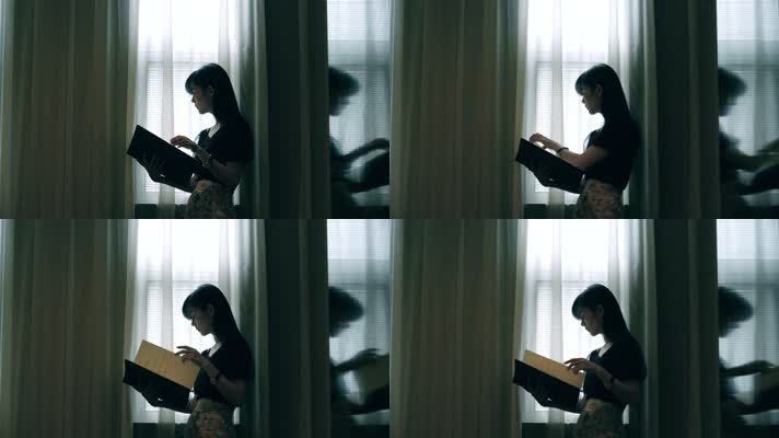 女孩在窗边翻看画册书籍4k