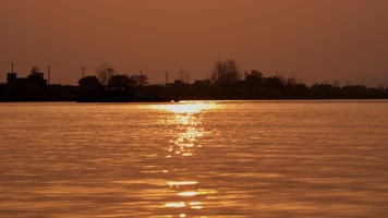 傍晚夕阳落日逆光金色水面轮船剪影